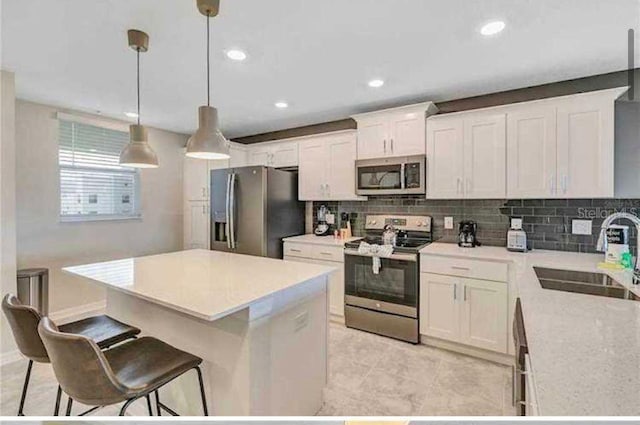 kitchen with decorative light fixtures, white cabinetry, sink, and appliances with stainless steel finishes