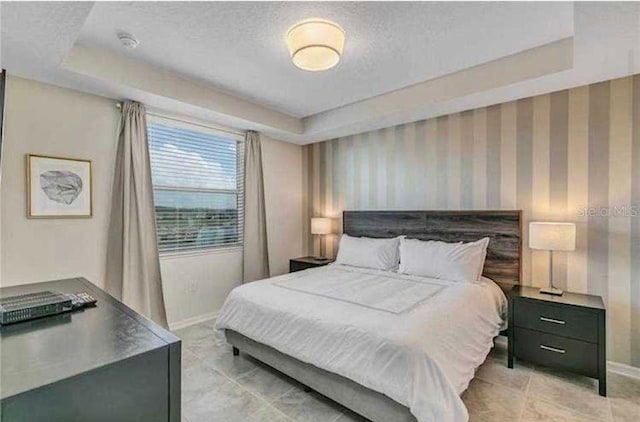 bedroom with a raised ceiling and a textured ceiling