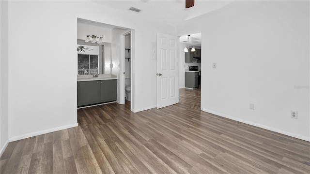 unfurnished living room with ceiling fan, dark wood-type flooring, and sink