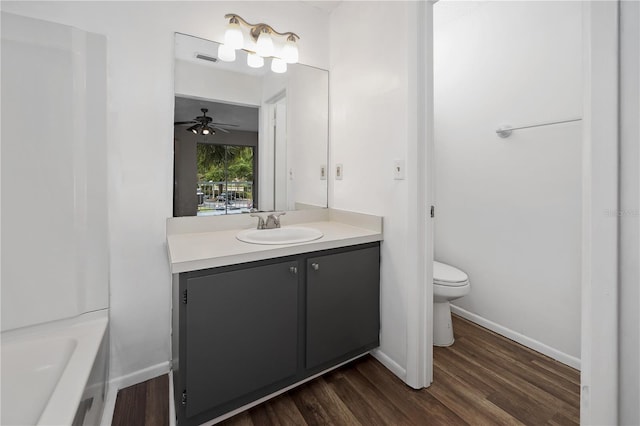 bathroom featuring a bathtub, vanity, ceiling fan, hardwood / wood-style floors, and toilet