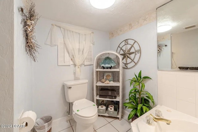 bathroom featuring tile patterned flooring, visible vents, toilet, and a bath