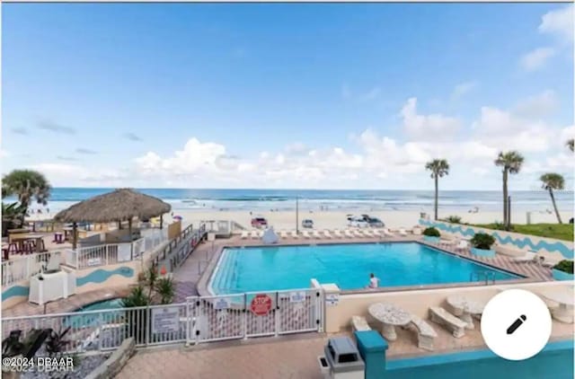 pool featuring a water view, fence, and a patio