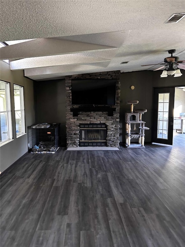 living room featuring a stone fireplace, ceiling fan, wood-type flooring, and a textured ceiling