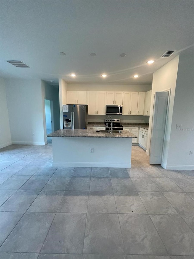 kitchen featuring white cabinets, appliances with stainless steel finishes, a center island with sink, and sink