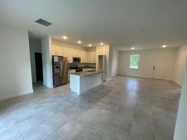 kitchen featuring appliances with stainless steel finishes, sink, light tile patterned floors, stone counters, and white cabinetry