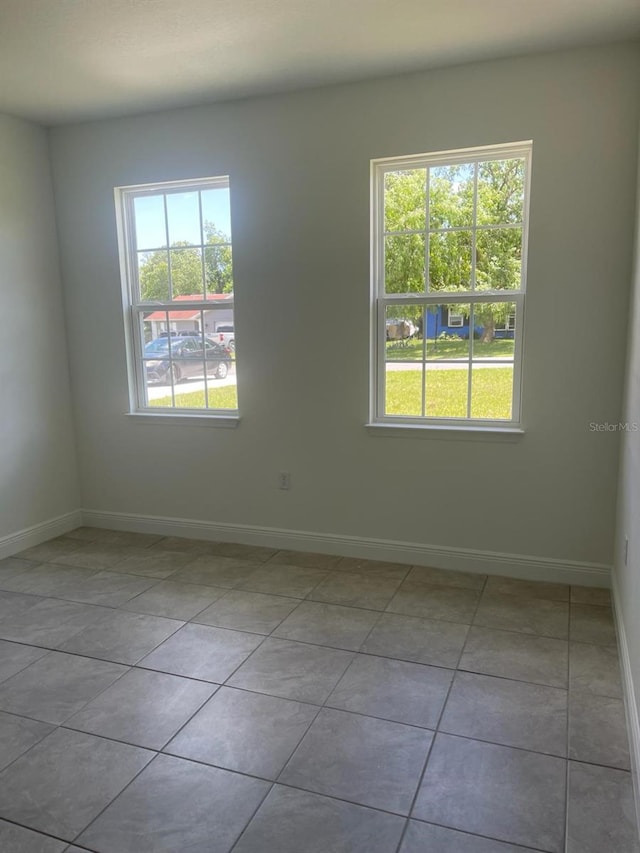 unfurnished room with light tile patterned floors and a healthy amount of sunlight