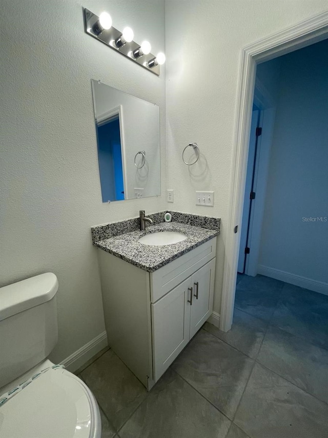 bathroom featuring tile patterned flooring, vanity, and toilet