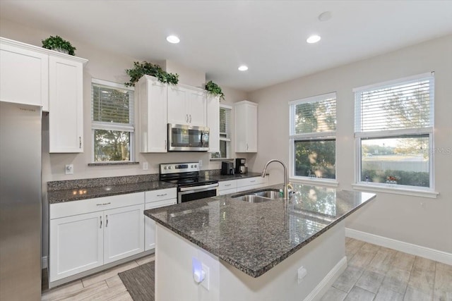 kitchen with white cabinets, appliances with stainless steel finishes, an island with sink, and sink