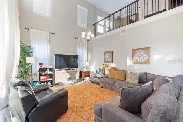 living room with plenty of natural light, a towering ceiling, and an inviting chandelier