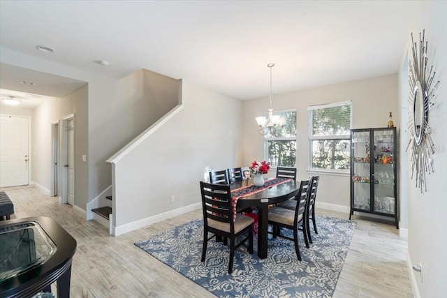 dining area with light hardwood / wood-style flooring and a notable chandelier