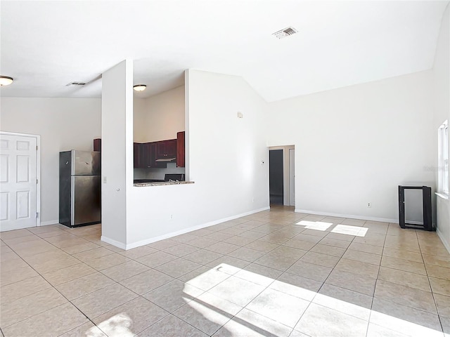 unfurnished living room with high vaulted ceiling and light tile patterned floors