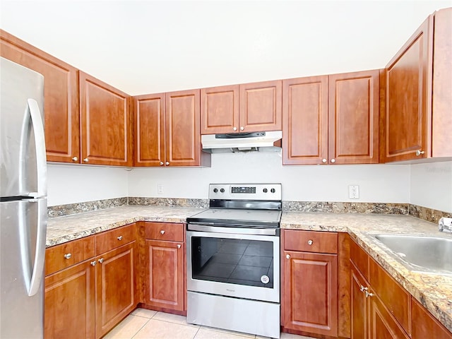 kitchen featuring light stone counters, stainless steel appliances, light tile patterned floors, and sink