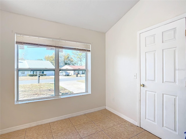 unfurnished room with light tile patterned flooring and vaulted ceiling