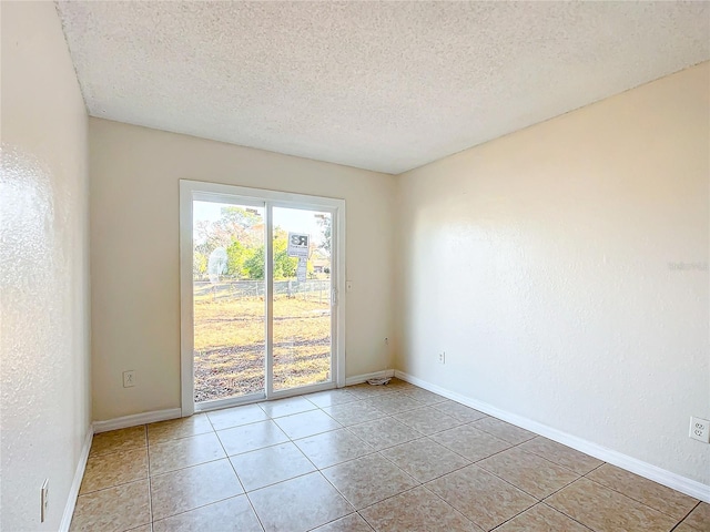 tiled empty room featuring a textured ceiling