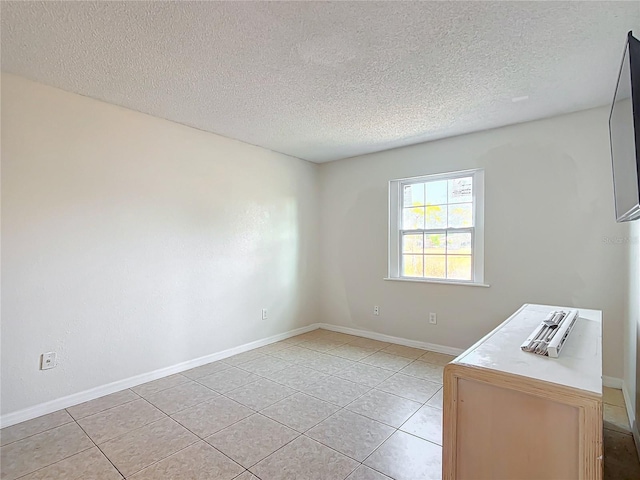 tiled empty room with a textured ceiling