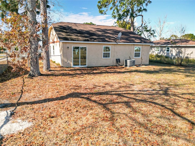 rear view of property featuring a lawn and central AC