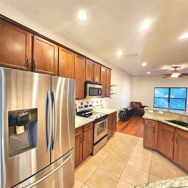 kitchen featuring light stone countertops, light tile patterned floors, and stainless steel appliances