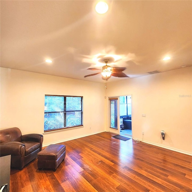 living room featuring ceiling fan, wood-type flooring, and a wealth of natural light