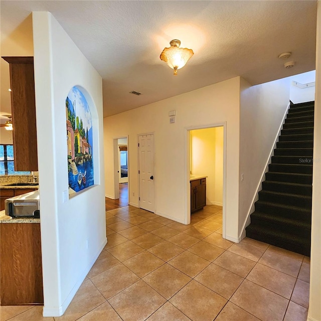 hall with sink, light tile patterned floors, and a textured ceiling