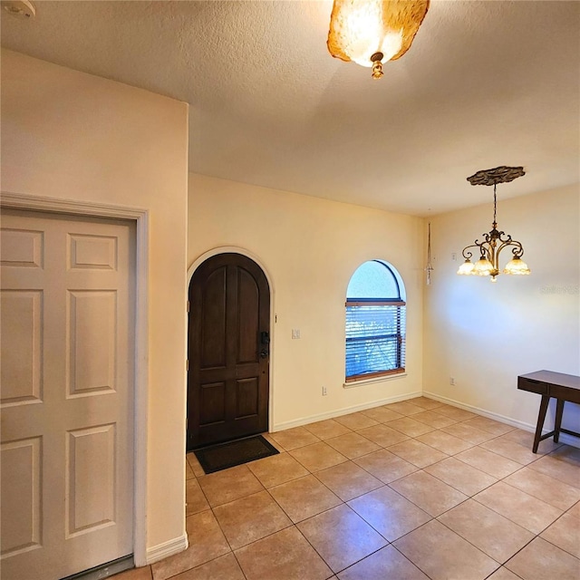 tiled entrance foyer featuring a notable chandelier