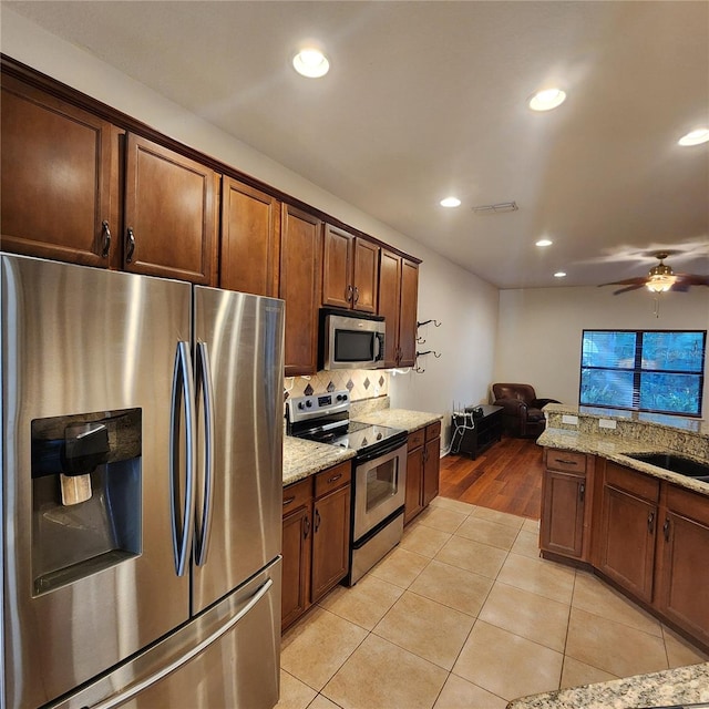 kitchen with light tile patterned floors, stainless steel appliances, and light stone counters