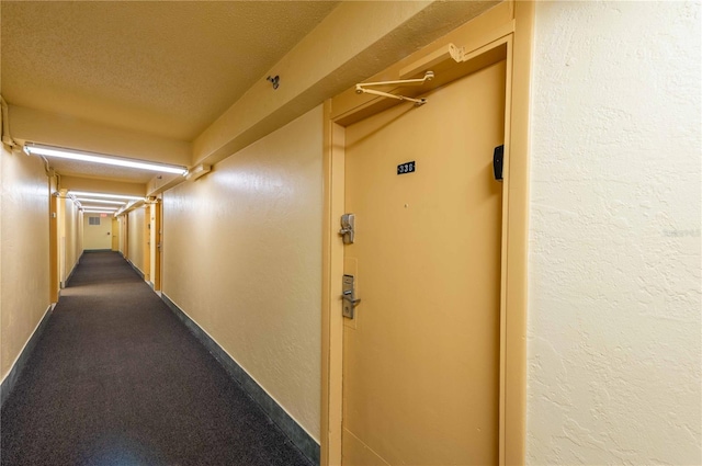 hall with a textured ceiling and carpet floors