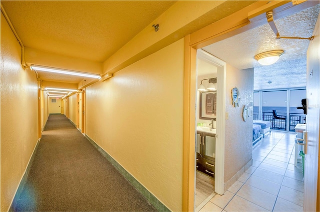 hall featuring tile patterned flooring, a water view, a textured ceiling, and sink