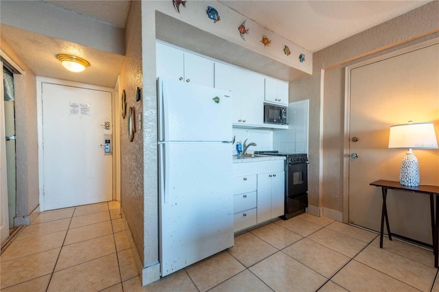 kitchen featuring black appliances, white cabinets, light tile patterned floors, and a textured ceiling