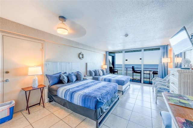 bedroom with a water view, ceiling fan, access to exterior, a textured ceiling, and light tile patterned flooring