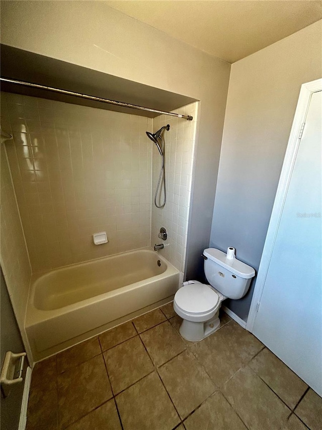 bathroom with tile patterned floors, tiled shower / bath combo, and toilet