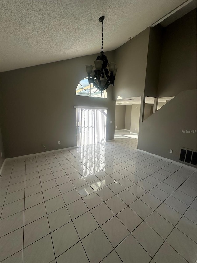 spare room with light tile patterned floors, a textured ceiling, a notable chandelier, and a high ceiling