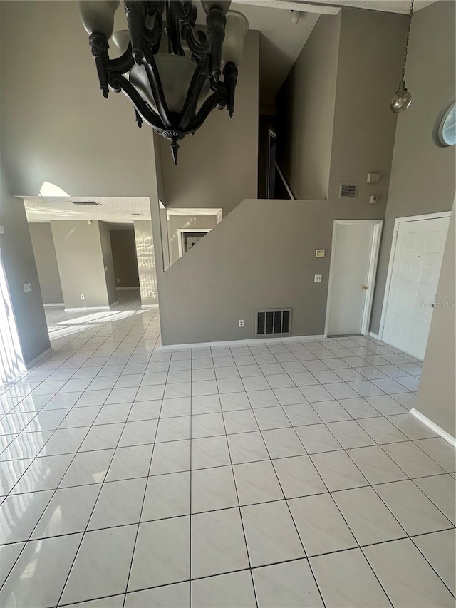 unfurnished living room with light tile patterned flooring, a high ceiling, and an inviting chandelier