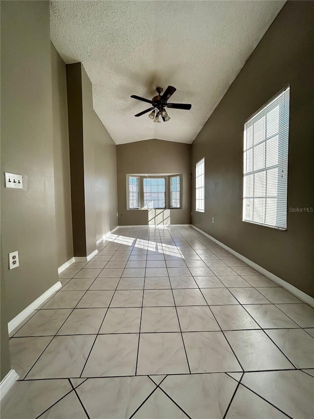 tiled empty room with a textured ceiling, vaulted ceiling, and ceiling fan