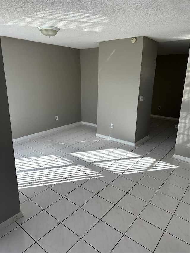 tiled empty room with a textured ceiling