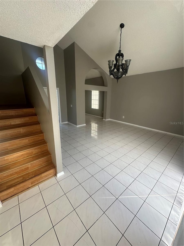 interior space featuring lofted ceiling, light tile patterned floors, a textured ceiling, and an inviting chandelier