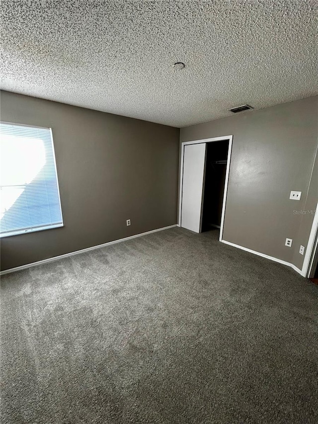 unfurnished bedroom featuring dark colored carpet and a textured ceiling