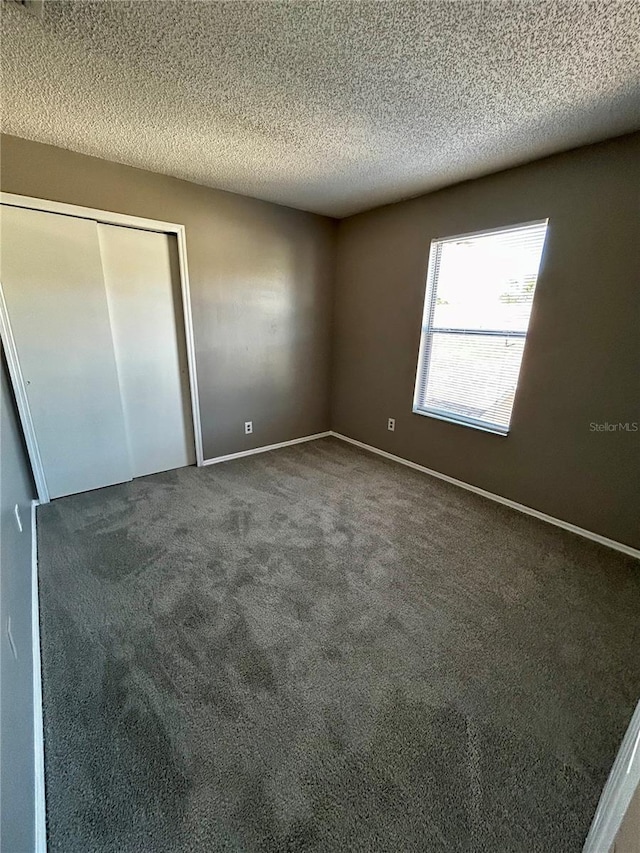 unfurnished bedroom with dark carpet and a textured ceiling