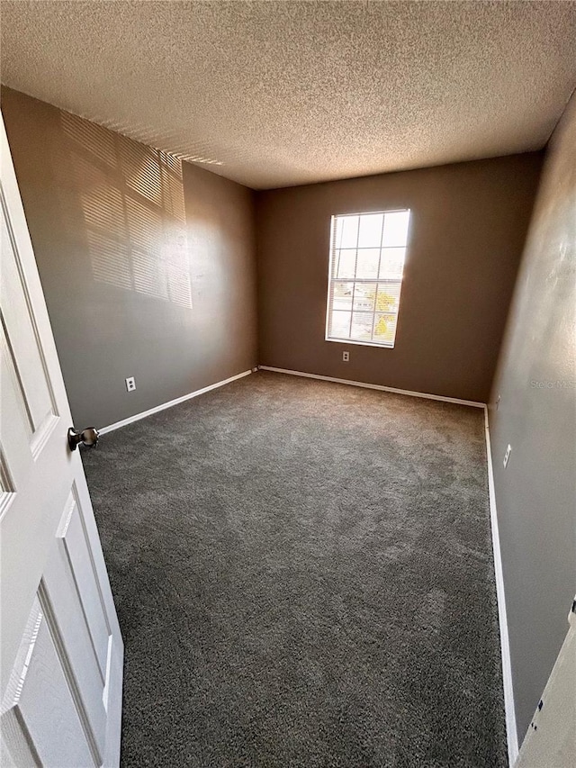 carpeted empty room featuring a textured ceiling