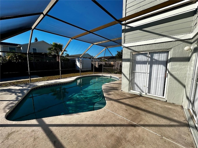 view of swimming pool featuring a patio, glass enclosure, and a shed