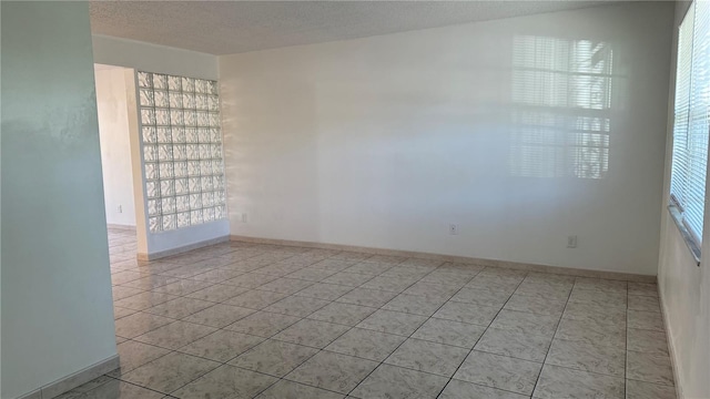 tiled spare room with a textured ceiling and a wealth of natural light