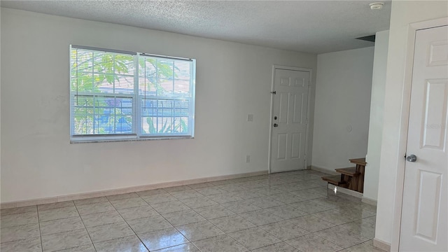 unfurnished room with light tile patterned floors and a textured ceiling