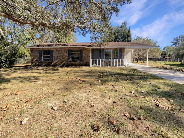 ranch-style house featuring a carport, covered porch, and a front lawn