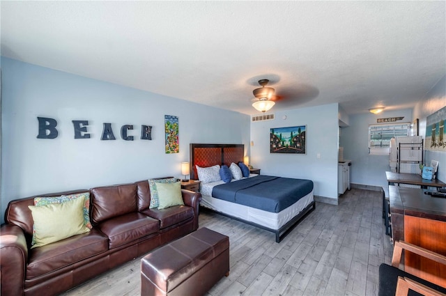 bedroom featuring ceiling fan, a textured ceiling, and light hardwood / wood-style flooring