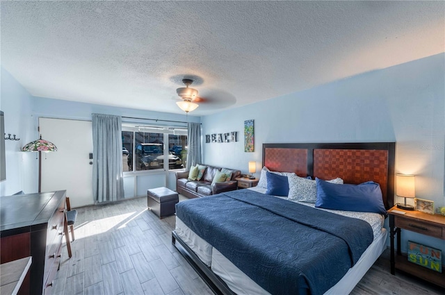 bedroom with ceiling fan, wood-type flooring, and a textured ceiling