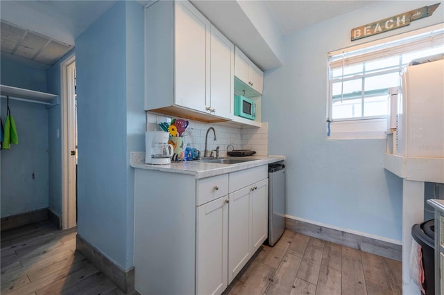 kitchen with decorative backsplash, sink, white cabinets, and light wood-type flooring