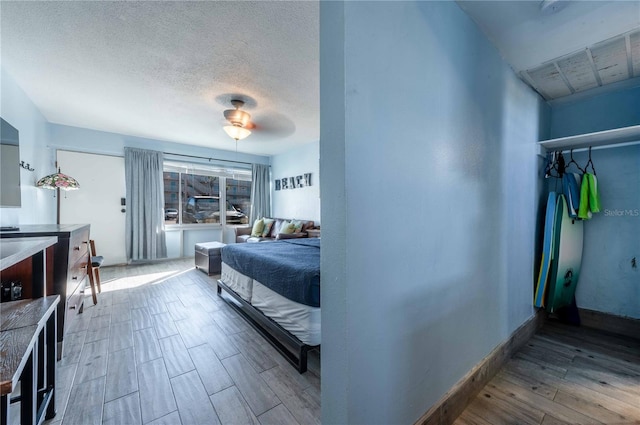 bedroom featuring ceiling fan, wood-type flooring, and a textured ceiling