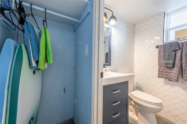 bathroom with tile patterned flooring, vanity, tile walls, and toilet