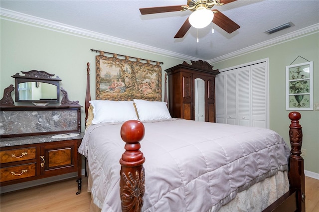 bedroom with ceiling fan, light wood-type flooring, crown molding, and a closet