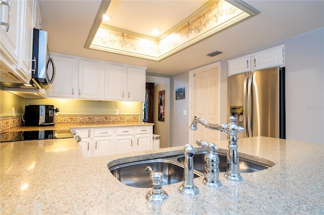 kitchen featuring white cabinets, a raised ceiling, sink, light stone countertops, and stainless steel appliances