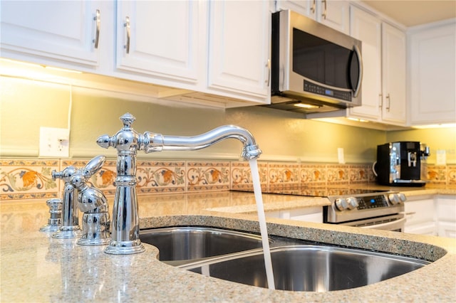 kitchen with white cabinets, light stone countertops, sink, and tasteful backsplash